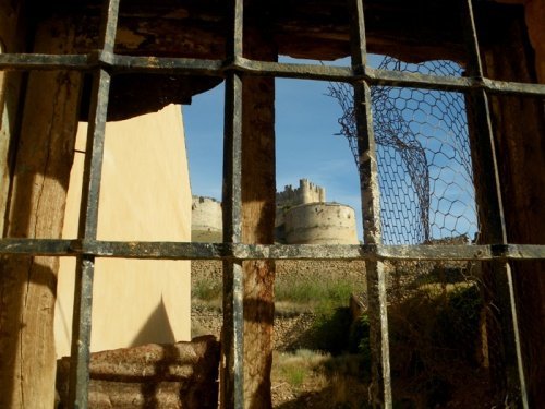 Tras las antiguas rejas, asoma del castillo de Berlanga de Duero