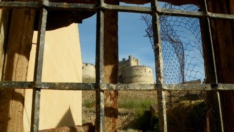 Tras las antiguas rejas, asoma del castillo de Berlanga de Duero